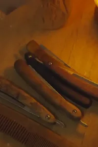 Peigne en bois et rasoirs traditionnels sur une table en bois, éclairés par une lampe de sel